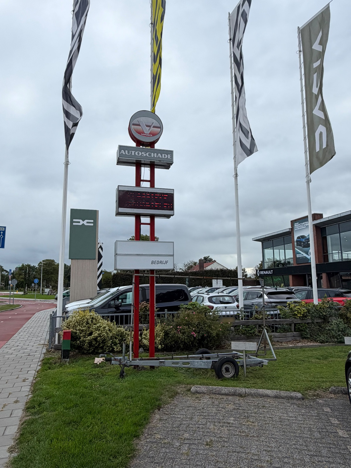 Het rode autoschadebord en de vlaggen langs de weg bij het terrein